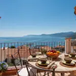 Terrazza attrezzata con tavolo da pranzo e vista mare in una casa vacanza in Sardegna