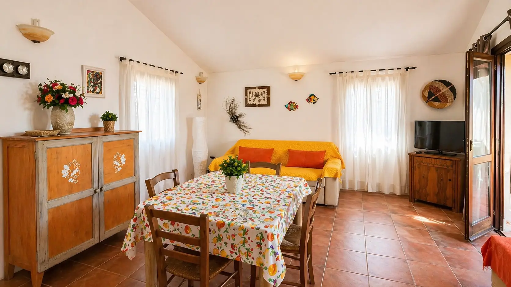 Soggiorno con tavolo da pranzo e divano giallo del Trilo Armonia, casa vacanza a Badesi