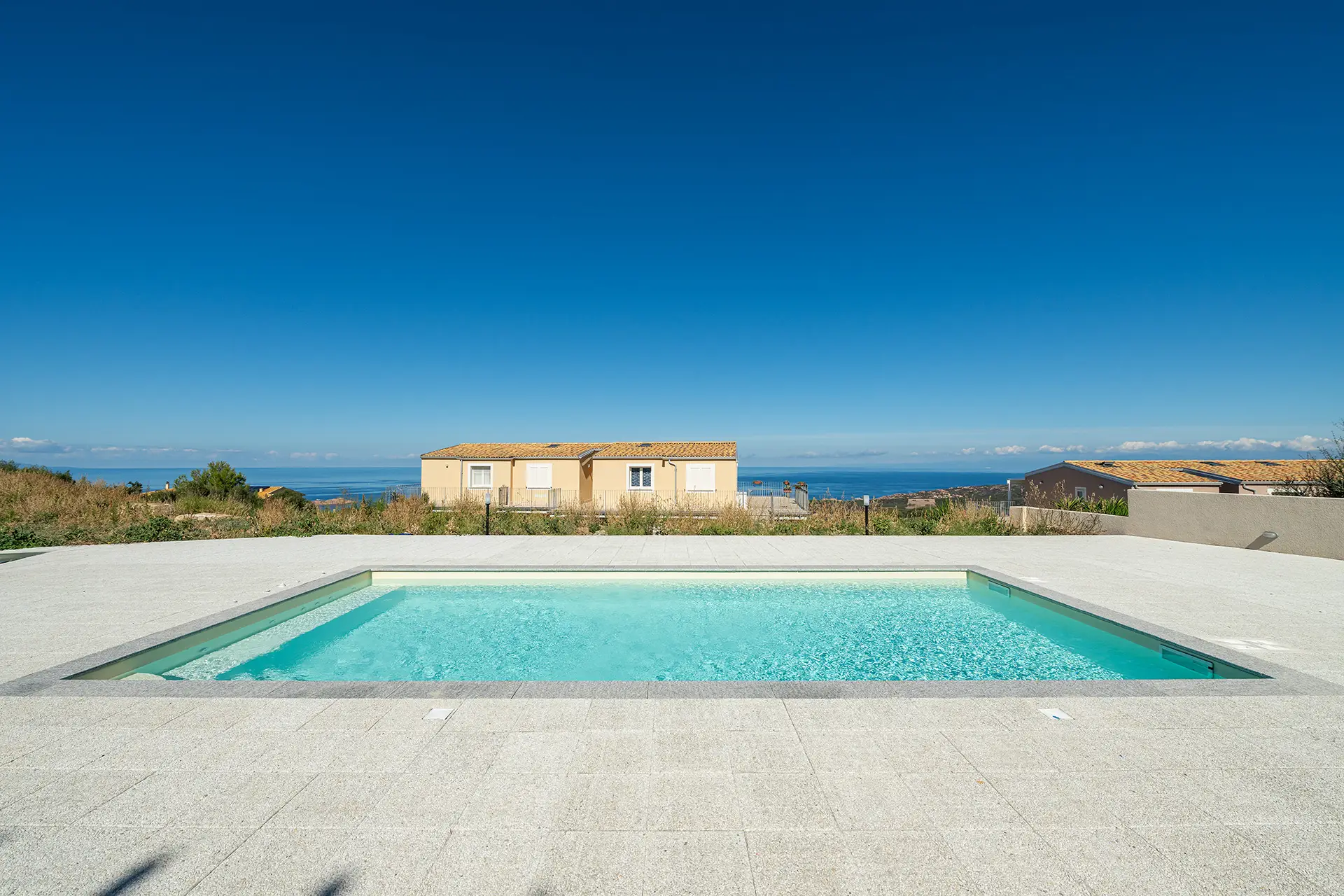 Piscina panoramica con vista mare e solarium in residence moderno in Sardegna